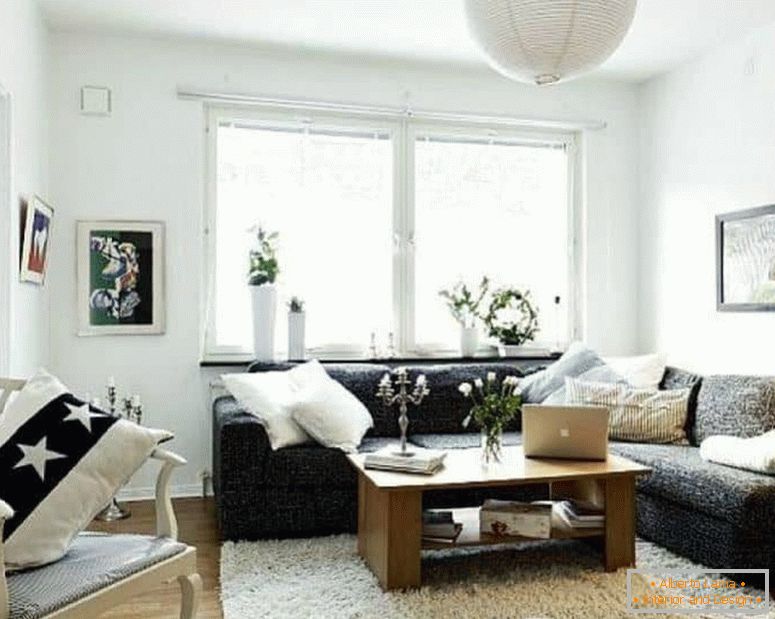 Un petit salon en blanc avec un canapé d'angle sombre et une fenêtre