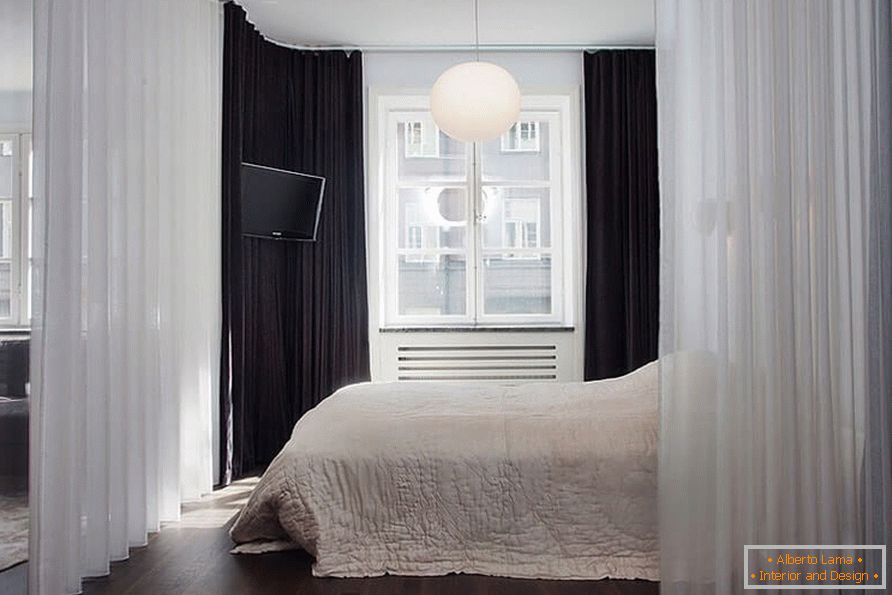 Un lit avec un rideau dans un appartement d'une pièce de 36 m²
