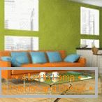 Canapé orange avec des oreillers bleus sur fond de mur de pistaches