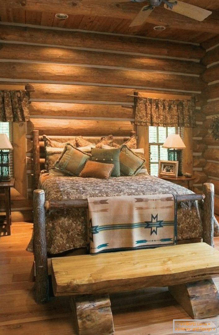 Un exemple classique de chambre à coucher dans un style rustique. Lit intéressant d'une maison en rondins brute et non traitée. 