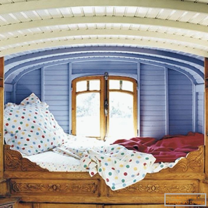 Détails minimes dans la chambre dans le style rustique. Le designer a choisi un endroit inhabituel pour le lit. Un petit lit à la fenêtre est le lit parfait pour les rêveurs.
