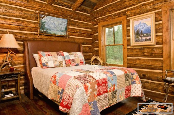 Une chambre dans un style rustique dans un pavillon de chasse. Décoration remarquable des murs avec l'aide d'une maison en rondins. 