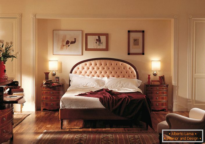 Le style anglais noble dans la chambre est attrayant et modeste. Le centre d'attention est un lit dans une tête de lit haute, qui est parsemé d'un doux tissu beige clair.