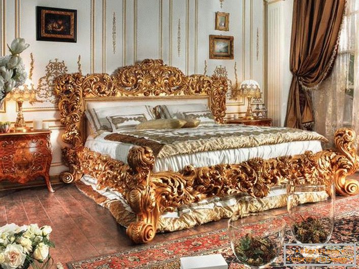 Un lit luxueux est fabriqué dans les meilleures traditions du style Empire. Le dos massif d'un lit de bois sculpté de couleur dorée noble se détache sur l'arrière-plan d'autres détails intérieurs.