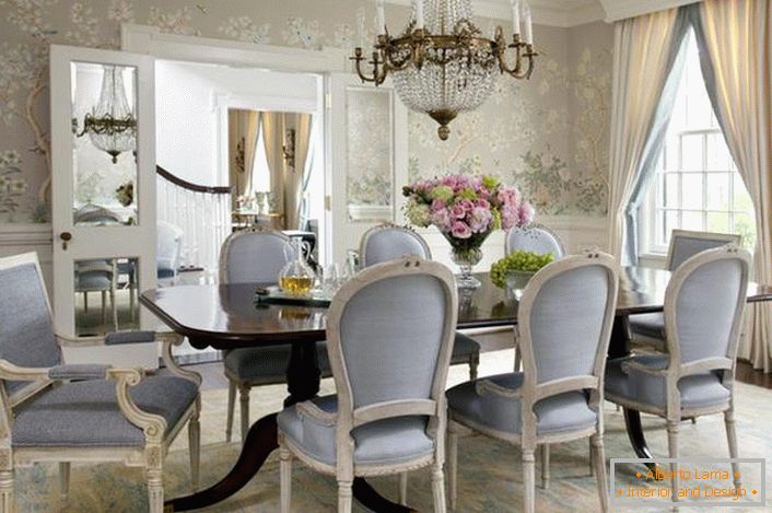 La salle à manger de style néoclassique est décorée dans des tons bleu pâle et gris clair. Le papier peint à fleurs se combine délicatement avec les hauts plinthes blanches.