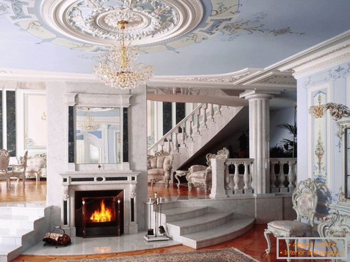 La salle avec une cheminée de style néoclassique se distingue par la palette de couleurs choisie pour la décoration. Une douce nuance bleue et blanche se mêle harmonieusement dans une composition unique.