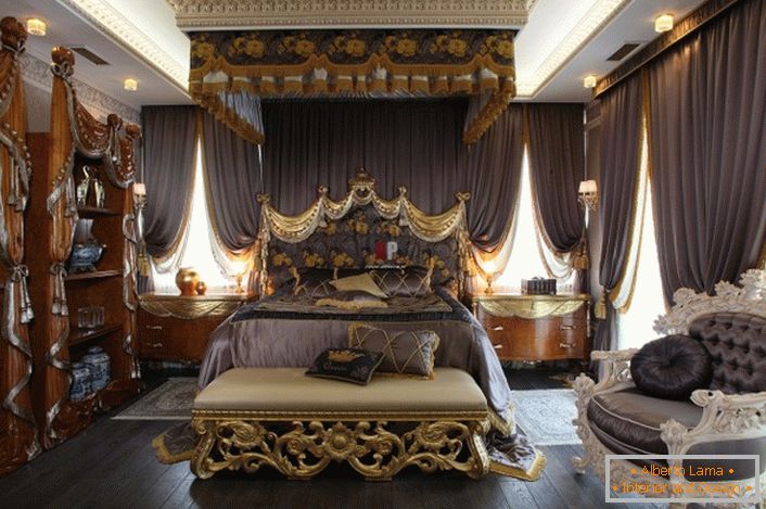 Chambre de luxe de style baroque. Au centre de la composition se trouve un lit massif avec une haute tête de lit décorée.