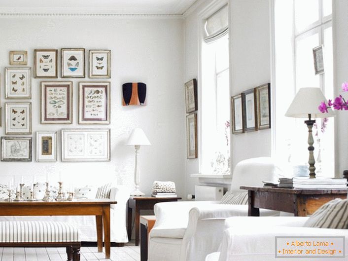 Un salon confortable dans le style scandinave est fabriqué en blanc. Il est intéressant de décorer le mur avec des cadres de différentes tailles.