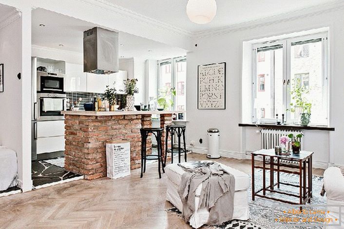 Le studio est décoré dans un style scandinave. La cuisine est séparée du salon par un comptoir en briques.
