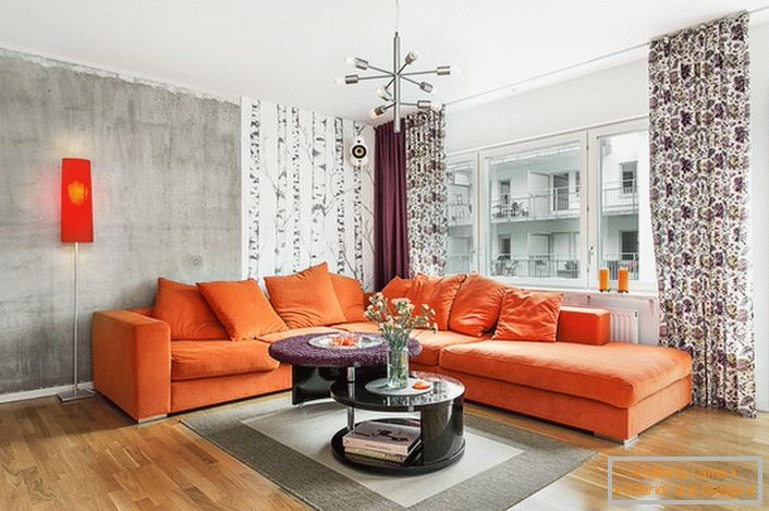 Le style scandinave est inhérent à l'utilisation de couleurs chaudes dans le design d'intérieur. Un canapé orange doux regarde organiquement sur le fond des murs d'une teinte gris froid.