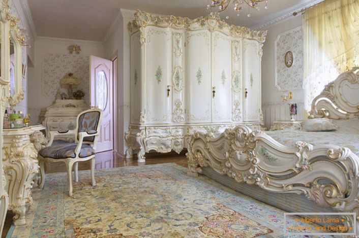 Chambre blanche comme neige avec des meubles massifs en bois sculptés. Le lit avec tête haute à la tête de lit s'intègre élégamment à l'intérieur dans le style baroque.