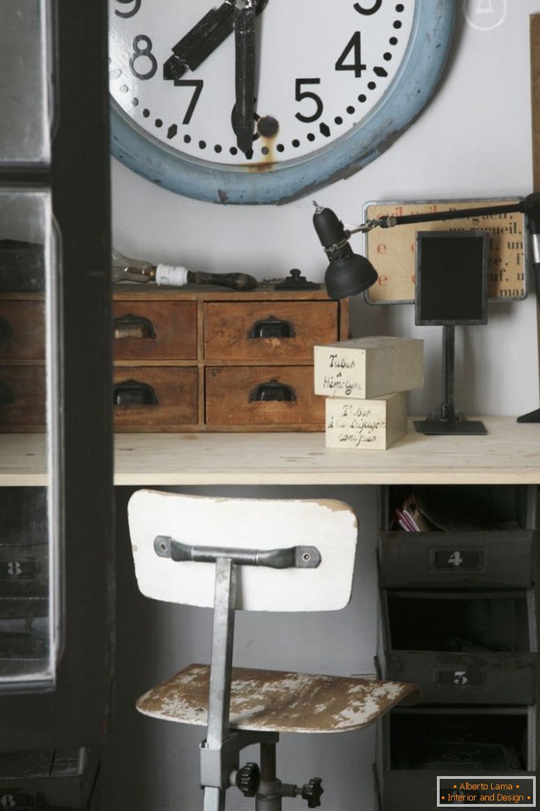 Ancienne horloge de gare au-dessus d'un bureau vintage avec des boîtes de rangement en bois et une chaise pivotante en bois avec de la peinture écaillée