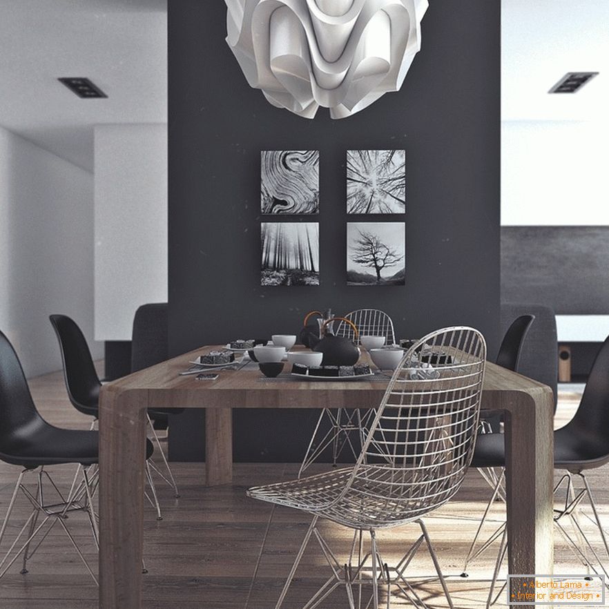 Une table à manger en bois, des chaises noires et des peintures originales sur un mur noir