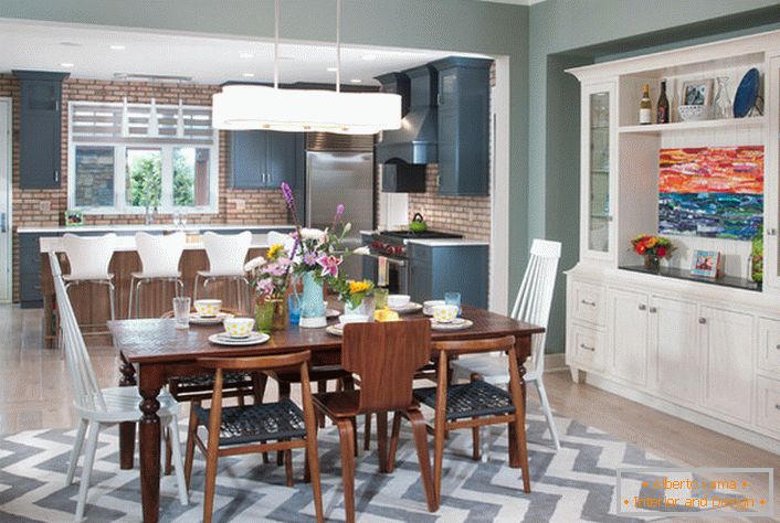 Une grande cuisine de style éclectique est divisée en un espace de travail et une salle à manger. Les meubles de couleur blanche sont combinés avec des éléments d'un intérieur de couleur brun foncé.