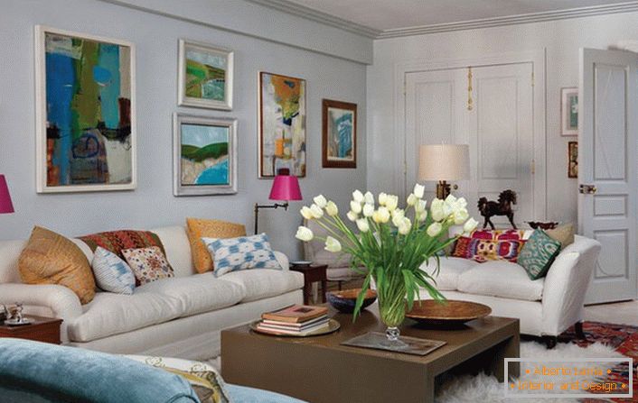 Salon universel de style éclectique. Une chambre confortable fait beaucoup d'oreillers et de peintures abstraites et lumineuses qui ornent le mur au-dessus du canapé.