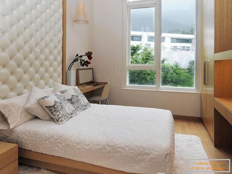 Un petit lit avec une tête de lit en cuir et dans la chambre avec une grande fenêtre