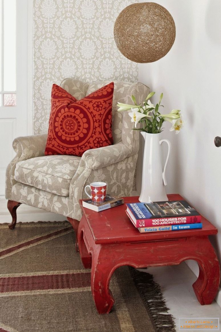 Coin lecture; table d'opium et fauteuil pâle avec coussins à motifs à motifs contre le mur peint