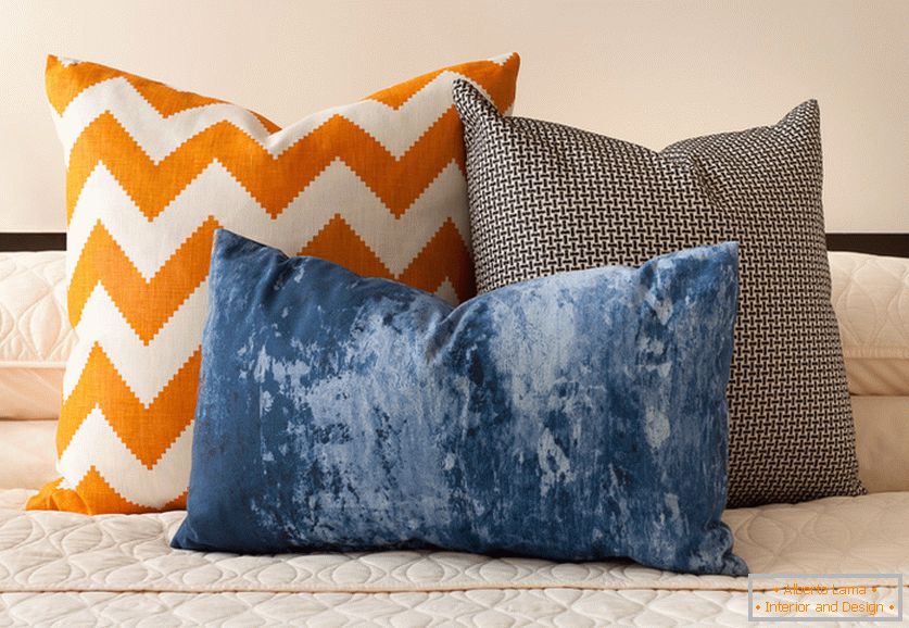 Orange, bleu et noir et blanc coussins décoratifs avec des impressions intéressantes sur le lit