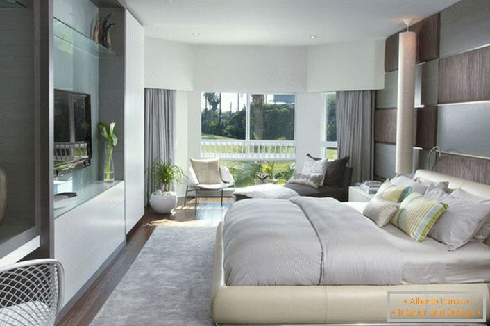 Lit moelleux en vrac dans la chambre à coucher dans un style moderne. Les meubles à surface brillante s'intègrent bien à la composition globale de l'intérieur.