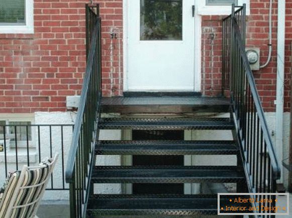Un petit porche en métal avec un escalier vers la maison en briques