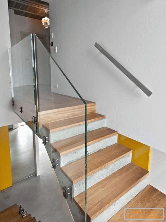 Escalier en béton avec marches en bois et garde-corps en verre dans une maison privée