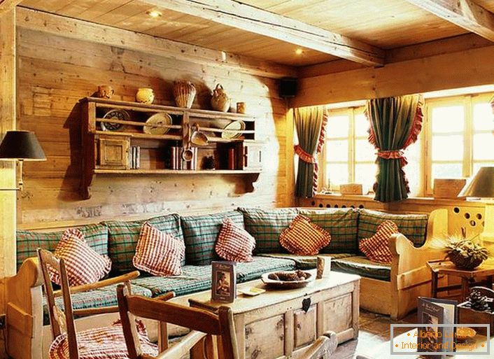 Décoration murale en bois, coussins contrastants sur un canapé moelleux, rideaux épais avec des volants sur les fenêtres. Salon confortable dans un style rustique dans une maison de campagne.