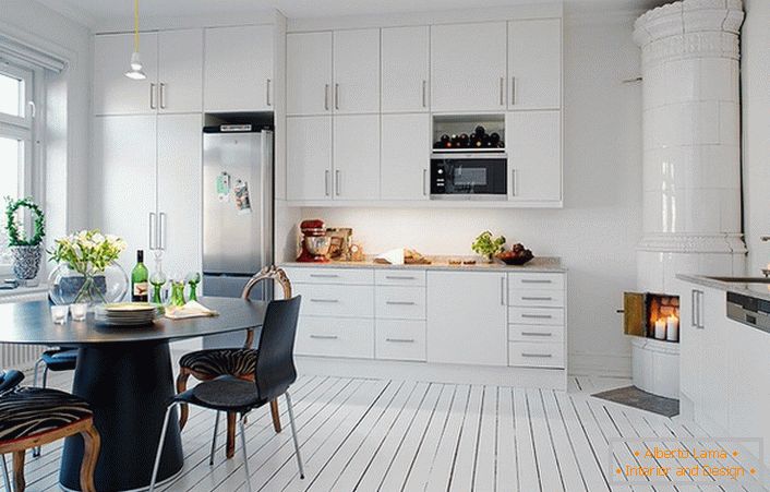 La cheminée carrelée, réalisée avec des carreaux de céramique blanche, s'inscrit naturellement dans l'intérieur de la cuisine dans un style scandinave.