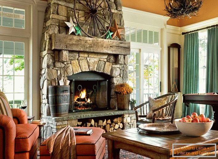 Une chambre spacieuse dans une maison de campagne de style champêtre. Il convient de noter les grandes fenêtres avec des cadres en bois et une grande cheminée en pierre naturelle.