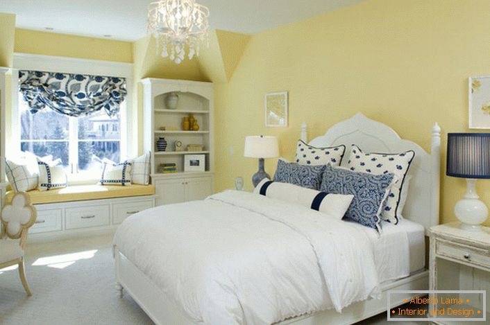 La couleur jaune délavée de la finition s'harmonise avec les éléments blancs et bleus du décor. Une combinaison inhabituelle est une solution audacieuse pour une chambre de style campagnard.