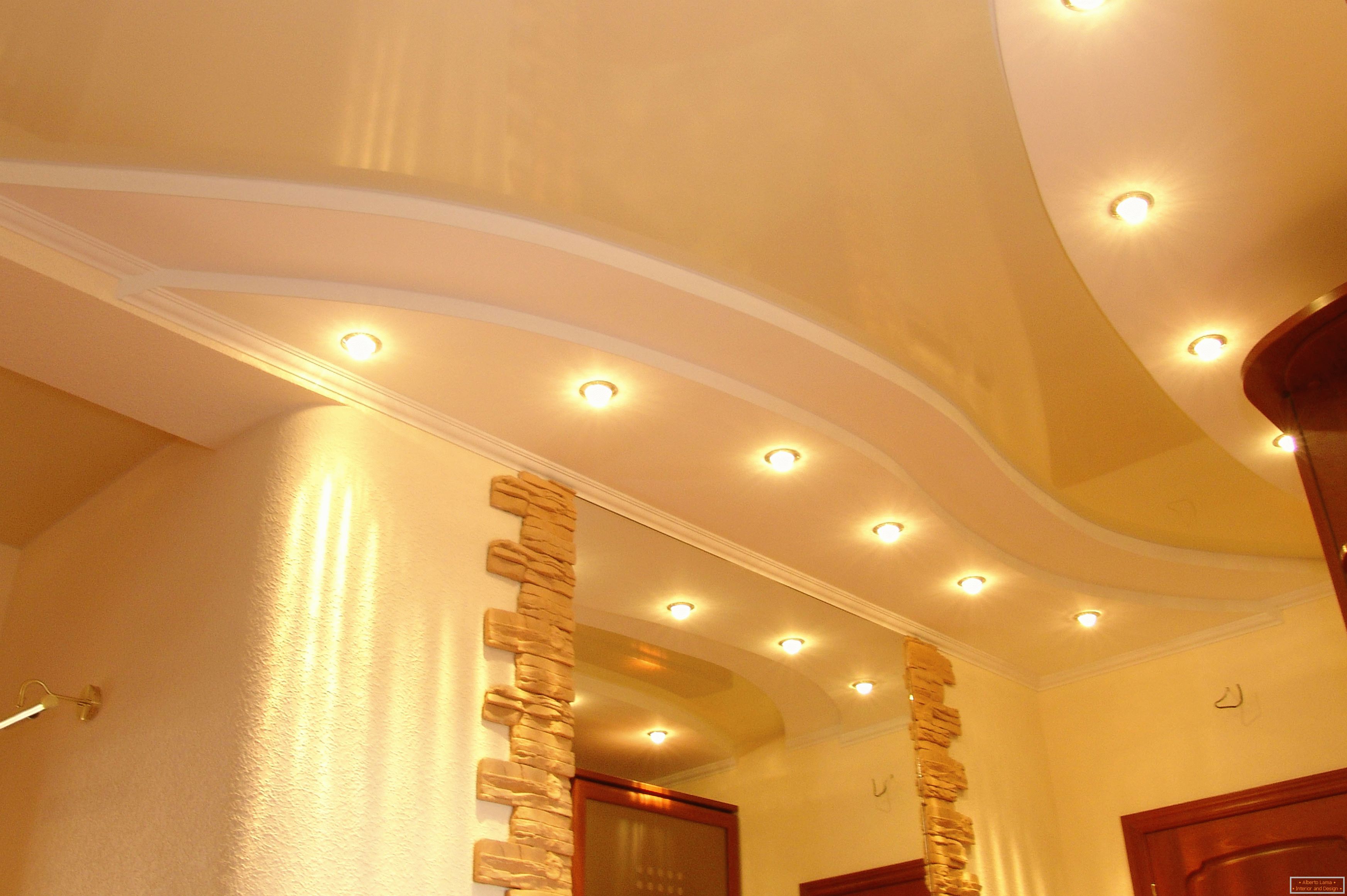 Plafond correctement décoré dans le couloir. Éclairage ponctuel - l'option la plus acceptable pour les plafonds tendus en PVC.