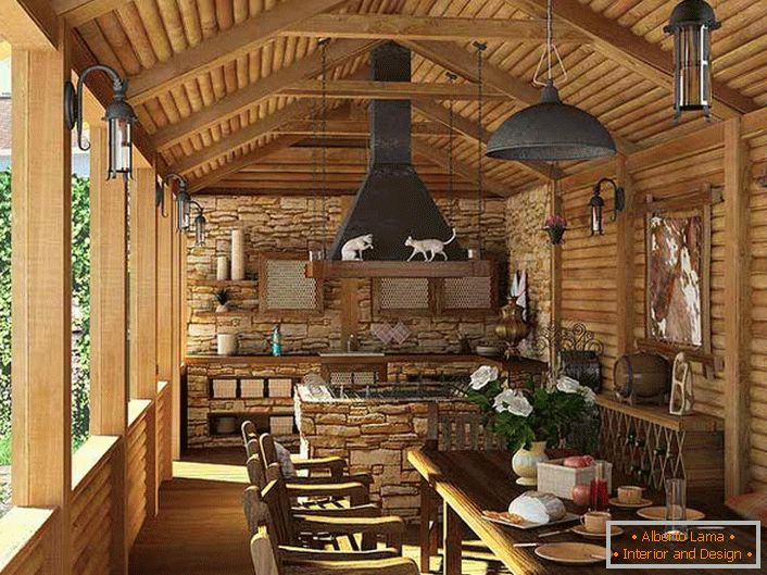 Une petite cuisine avec un barbecue sur la véranda d'une maison de campagne. Le style campagnard se manifeste d'abord par la décoration des murs et du plafond avec un cadre en bois.