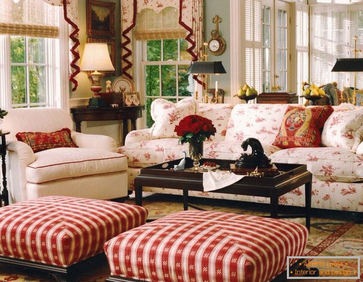 Un salon simple, modeste et confortable dans un style anglais dans une petite maison de campagne. Les accents de rouge rendent l'atmosphère dans la chambre détendue et joyeuse.