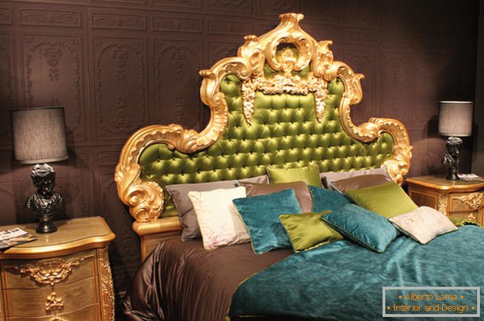 Un haut orné dans la tête du lit est recouvert de soie olive. Oreillers intéressants de couleurs contrastantes et couvre-lits sur le lit.
