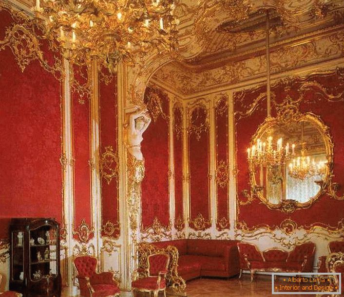 Le salon de la maison est correctement décoré avec des meubles rouges. Le rouge noble est parfaitement combiné avec des éléments de finition dorés.