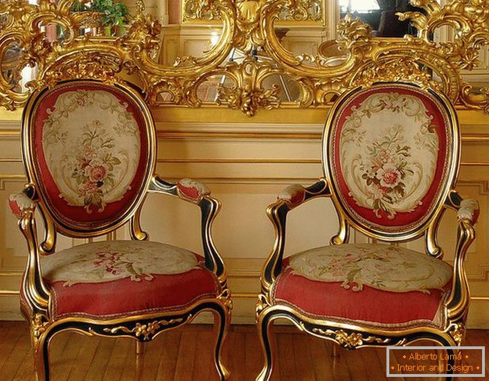 Stuc ajouré de couleur or sur le miroir et des chaises avec des tissus d'ameublement doux rouges - représentants lumineux du style baroque.