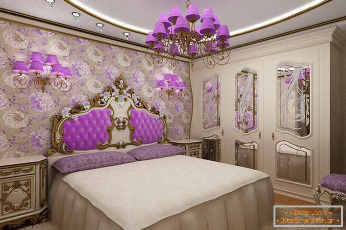Elégante chambre baroque avec un accent intéressant sur la lumière. Le lustre et les lampes de chevet avec les mêmes nuances violettes se combinent harmonieusement avec le rembourrage du dossier à la tête du lit.